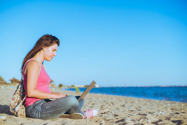 istock Woman using laptop on the beach 1098023370