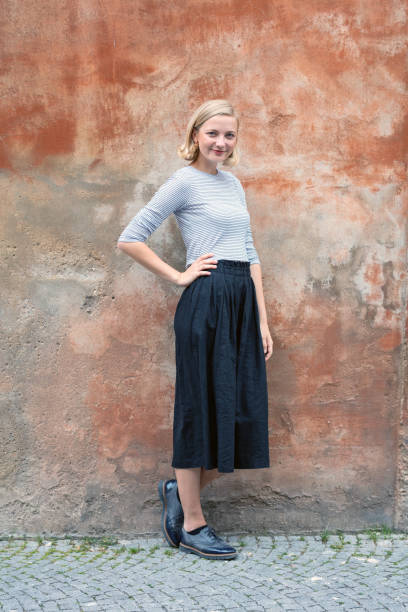 istock Confident young woman standing on a red wall 1098024244