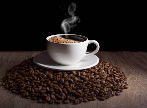istock coffee cup with steam at dark on the coffee beans stack 1098026612
