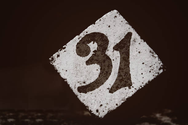 number 31 painted on a white concrete cube with a dark brown blurred background