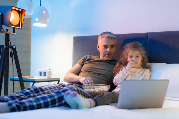 istock Grey-haired father and his small pretty daughter eating popcorn 1098031898