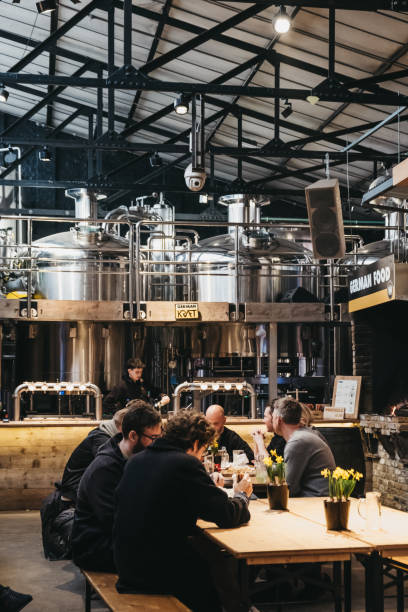 pessoas sentadas por cervejas artesanais ficar no mercado mercato metropolitano em londres, uk. - business styles foods and drinks drinking - fotografias e filmes do acervo