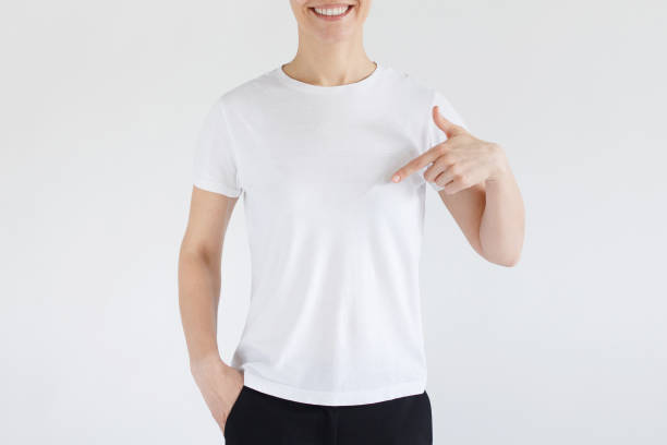 istock Young woman smiling while pointing with index finger to white t-shirt, copyspace for advertising, isolated on gray background. No face photo 1098036024