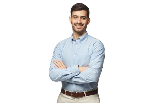 Apuesto hombre de negocios sonriendo en pie azul de la camisa con los brazos cruzados, aislado sobre fondo blanco photo