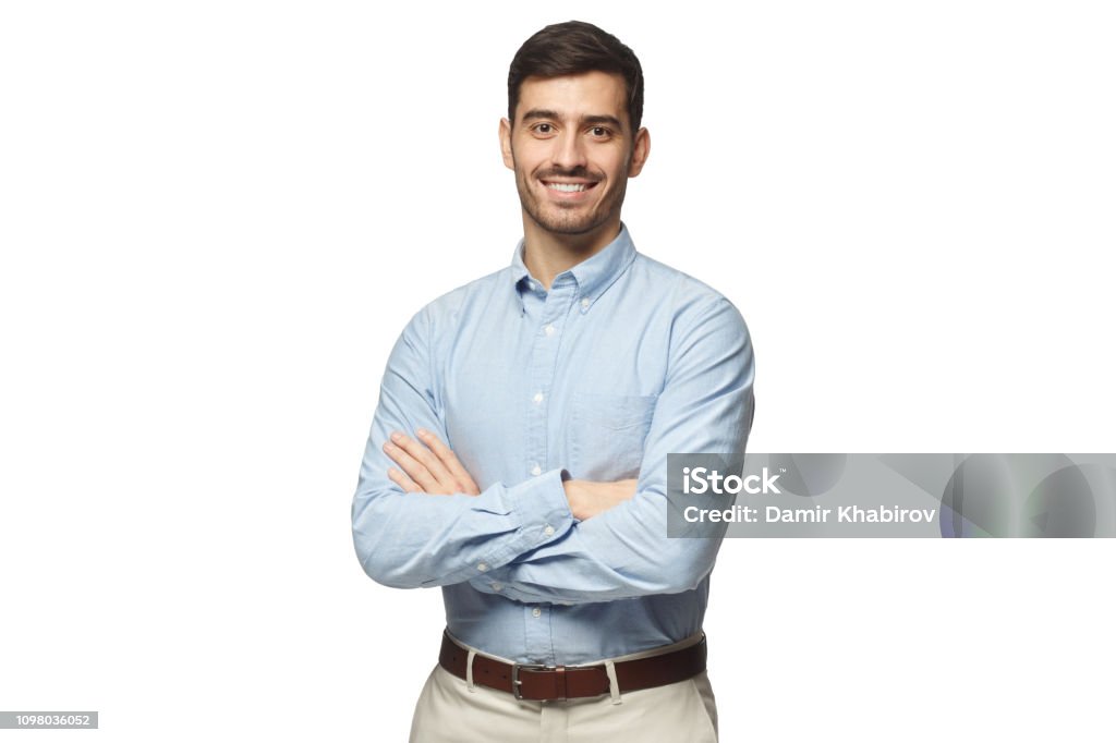 Apuesto hombre de negocios sonriendo en pie azul de la camisa con los brazos cruzados, aislado sobre fondo blanco - Foto de stock de Hombres libre de derechos