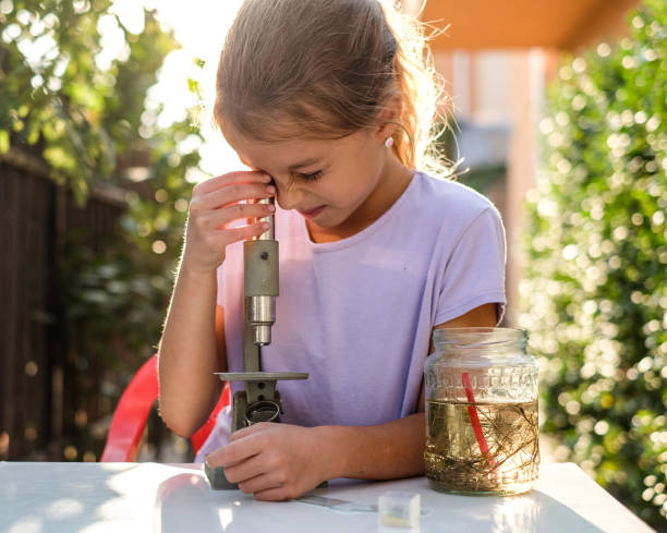 Cute little girl looking through the microscope Beauty girl love biology, looking at the microscope outdoors at sunny day ciliophora stock pictures, royalty-free photos & images