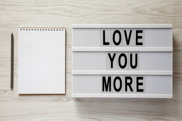 istock Lightbox with text 'Love you more', blank notepad and pencil on a white wooden background. Valentine's Day 14 February. 1098038570