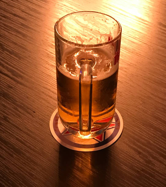 istock Beer mug on coasters on wooden table and light reflection in dark golden color 1098040618