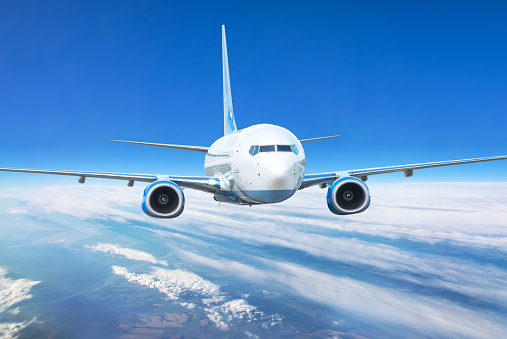 Close up view airplane in flight. Passenger jet plane in the blue sky. Aircraft flying high through clouds