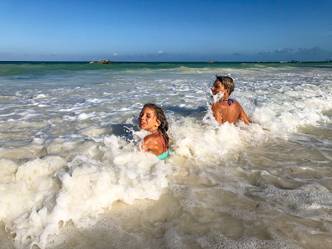 Mother and Daughter Enjoy Playing with Waves on Tropical Beach