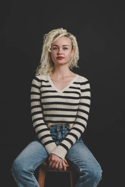 istock Young women sitting on chair over black background 1098058132