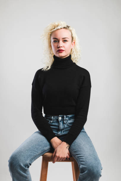 istock Young women sitting on chair over grey background 1098058334