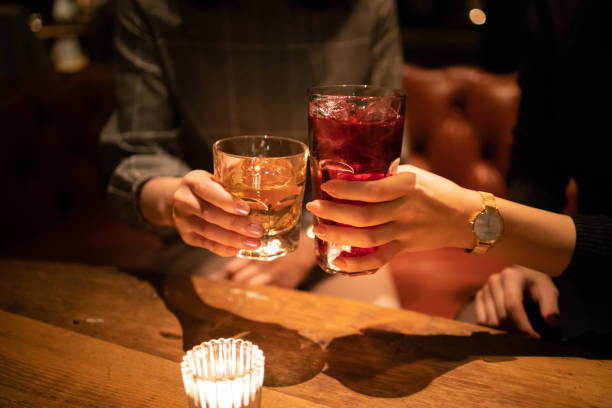 young female friends toasting glass after work - whisky cocktail alcohol glass imagens e fotografias de stock