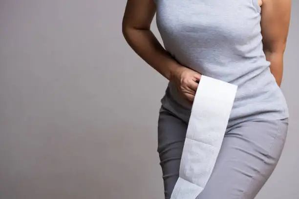 Woman hand holding her bottom and tissue or toilet paper roll. Disorder, Diarrhea, Constipation. Healthcare concept.