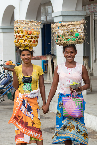 Toliara, Madagascar - January 10th, 2019: Two local malagasy woman with baskets on their head selling fruits in the streets at the market in Toliara, Madagascar.