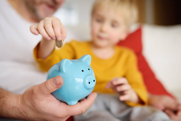Father and son putting coin into piggy bank Father and son putting coin into piggy bank. Education of children in financial literacy allowance stock pictures, royalty-free photos & images