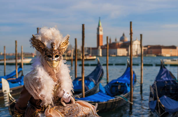 Venice Carnival Mask with Gondolas Venice, Italy - February 26, 2017: Beautiful Venetian Mask invites you to Venice Carnival, with St George Island, lagoon and gondolas in the background gondola traditional boat photos stock pictures, royalty-free photos & images