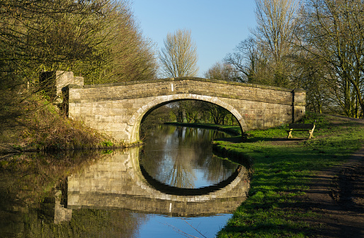 Reflections of old stone bridge on the Leeds/ Liverpool canal.  England/ UK.