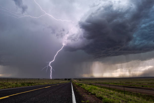 Lightning strike from a thunderstorm Lightning bolt strike from a thunderstorm with dark clouds and rain. dark road stock pictures, royalty-free photos & images