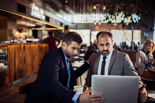 Close up of two businessman having coffee in a cafe while working