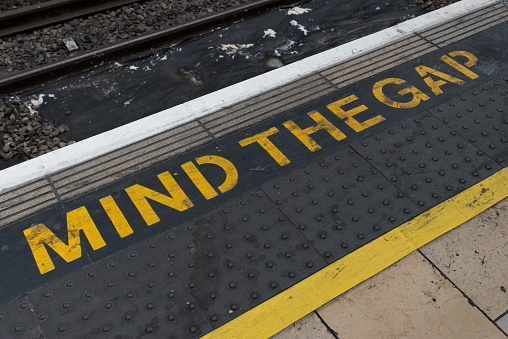 London, UK - Jul 27, 2017: Mind the gap written at the edge of the boarding area at the famous Paddington Train station late in the day.