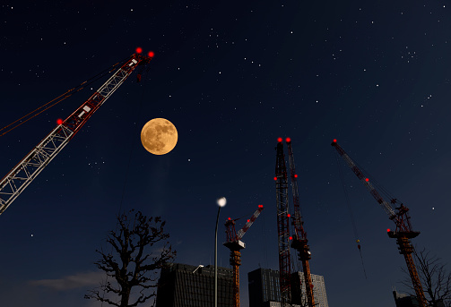 Low angle view of full moon rising over the Crane with copy space.