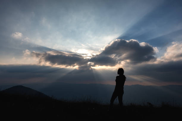istock A woman standing and watching sunset with mountains view 1098151952