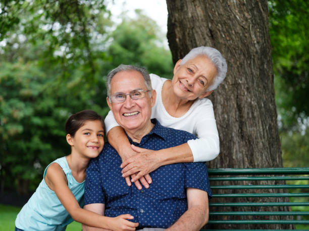 Happy grandparents and grandchild Happy grandparents and grandchild smiling at the camera senior adult women park bench 70s stock pictures, royalty-free photos & images
