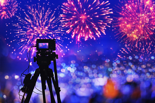 silhouette digital camera on tripod recording beautiful fireworks for celebrate in low light