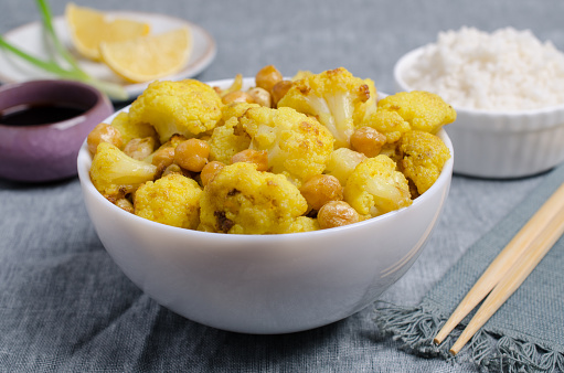 Roasted cauliflower with chickpeas and white rice on textile background. Selective focus.