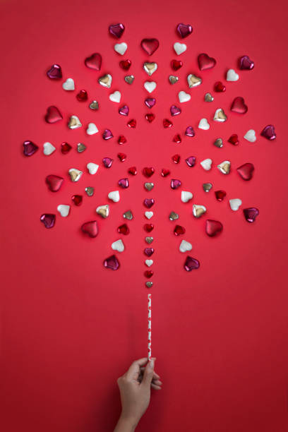 Hand lit up fireworks form by heart shape ornament on red background.