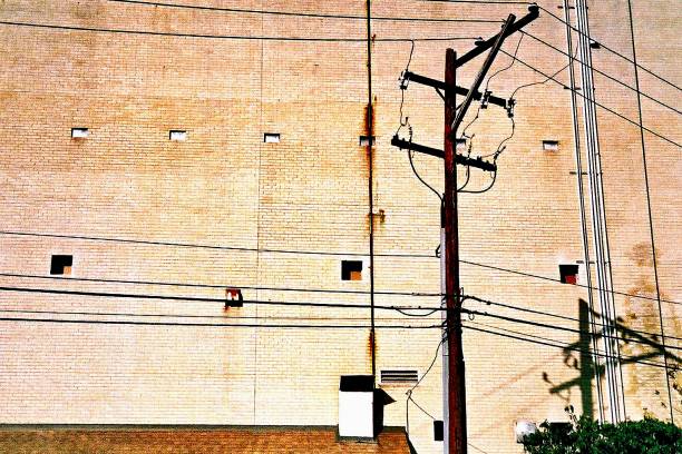 istock Power lines and electric pole against brick wall with window - low angle view 1098167000