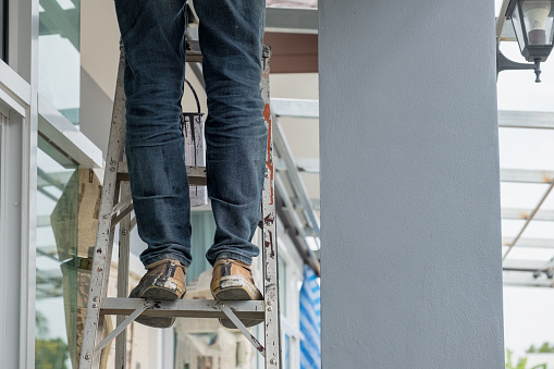 Construction worker wear jean pant standing on aluminium stairs