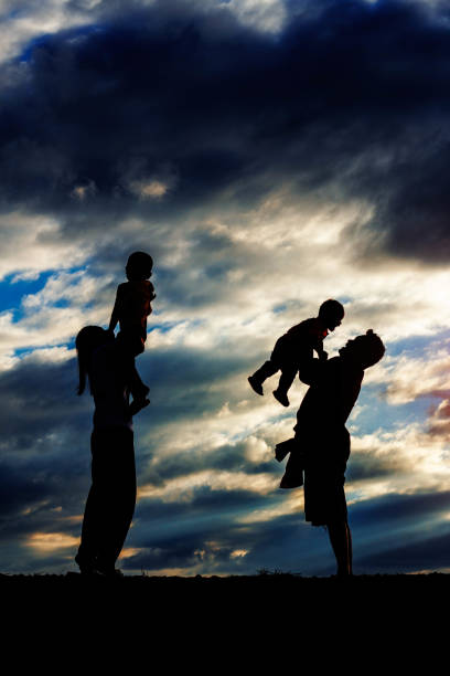 Happy family of parents and children playing at the sunset.