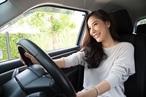 Las mujeres asiáticas que conducir un coche y una sonrisa feliz con expresión positiva alegre durante la impulsión a viajar viaje, gente disfrutar riendo transporte y relajada feliz mujer en concepto de vacaciones roadtrip photo