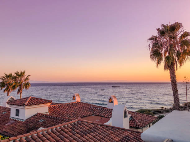 Sunset sky over Pacific ocean, view from a top floor Sunset over Pacific ocean near Santa Barbara, USA; rooftops and palm trees - view from a hotel on the coast santa barbara california stock pictures, royalty-free photos & images