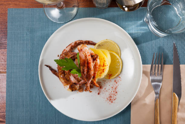 istock Delicious cooked squid or octopus tentacles with lemon and parsley on a plate 1098192618