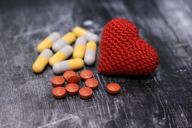 pastillas y punto corazón rojo en la mesa de madera vintage, enfoque selectivo - blood cardiologist color image nobody fotografías e imágenes de stock