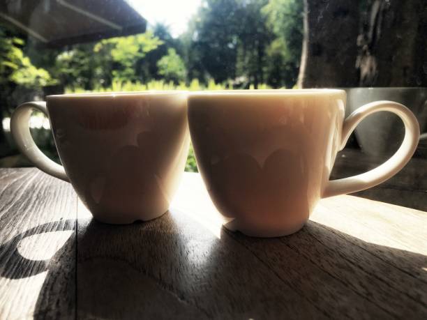 istock Twin white cup soft focus on wooden table with sunshine reflection. Left cup have  Red lipstick color as lips dirty on edge after woman sip the tea opposite with right cup that sip by man. 1098195566