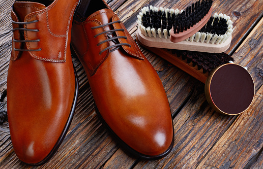 Men leather shoes and cleaning products on wood