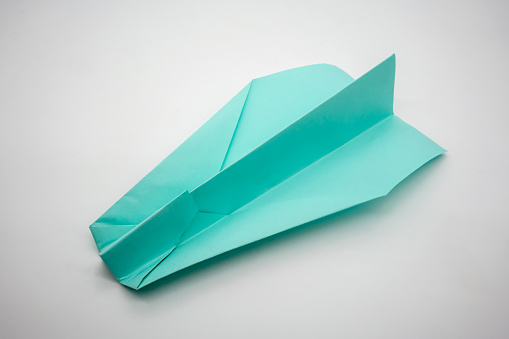 Light blue green origami paper airplane isolated on white background. Kid education concept.
