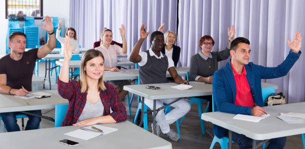 istock Adult people raising hands in classroom 1098197740