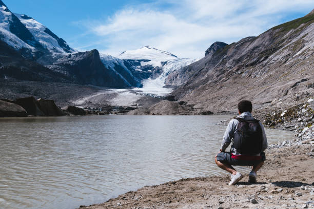 istock Man by lake looking at Alpine glacier 1098203136