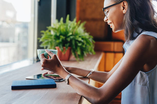 istock Smiling woman holding a cup while browsing files on digital tablet 1098205104
