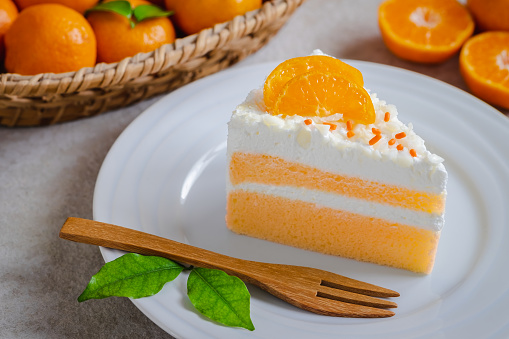 Orange cake on plate and fresh orange in basket
