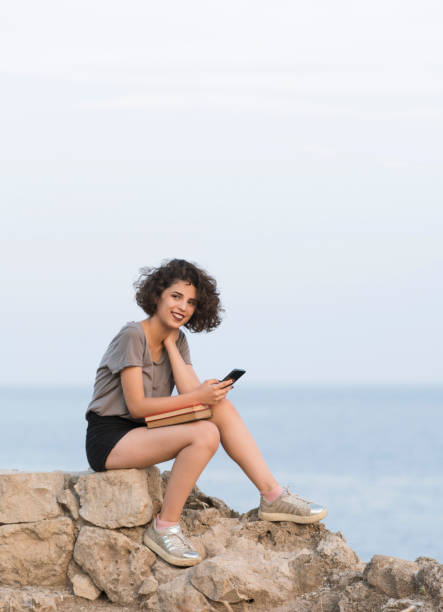 istock Young woman sitting rocks reading a book 1098207690