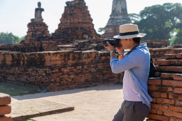 ost-asien sommerferien. touristen-kaukasischen mann von hinten betrachtet man wat chaiwatthanaram tempel. reisende fotografieren mit dslr-kameras. reisen sie in der altstadt von ayutthaya, thailand. asien-touristen. - wat chaiwattanaram stock-fotos und bilder