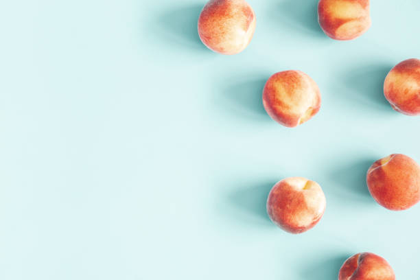 istock Peaches on pastel blue background. Frame made of fresh peashes. Flat lay, top view, copy space 1098217486