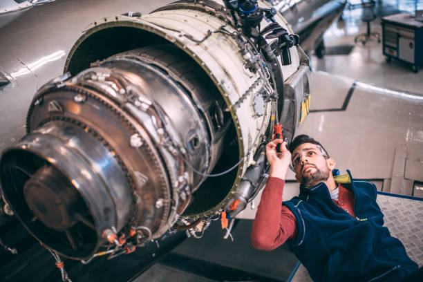 istock Aircraft mechanic lying down below a jet engine of a small airplane doing some maintenance to it in a hangar 1098230006