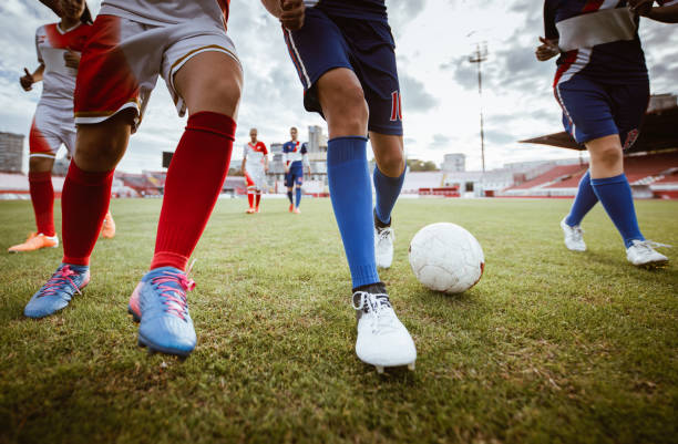 Unrecognizable soccer player keeping the ball away from her rival during the match on playing field. Skilful female soccer player dribbling the ball on a soccer match at stadium. soccer striker stock pictures, royalty-free photos & images